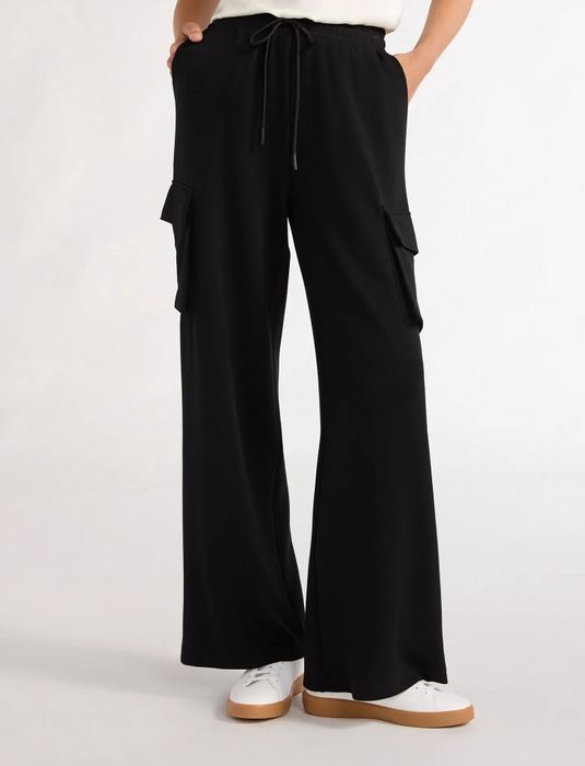 Person dressed in wide-leg black cargo pants paired with white sneakers