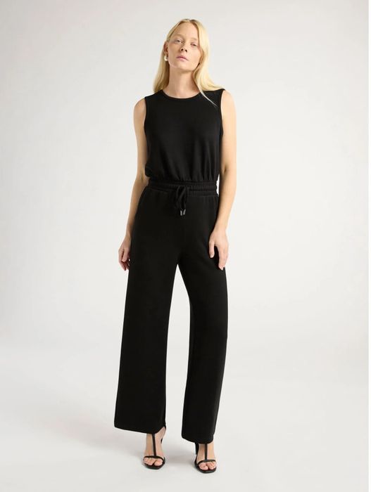 Person modeling a sleeveless, wide-leg jumpsuit with a drawstring waist and open-toe heels, suitable for both casual and dressy occasions