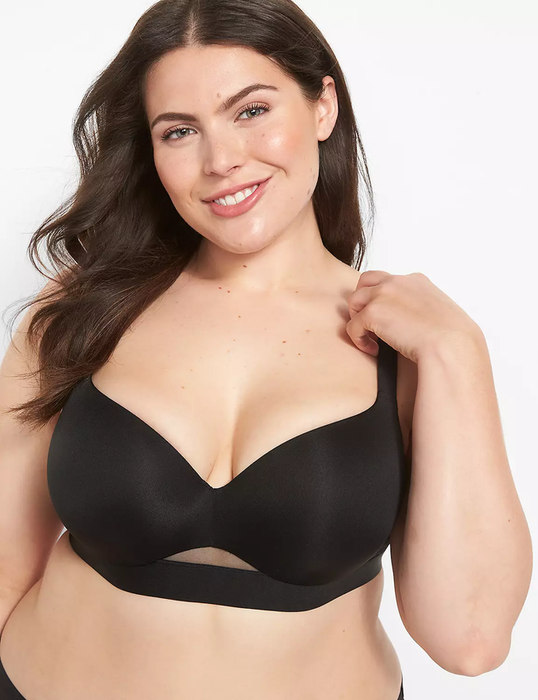 A model wearing a supportive black bra with a stylish mesh detail, flashing a smile for the camera in a fashion shopping article.