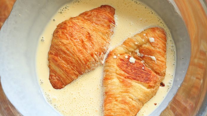 Croissant halves soaking in a rich custard mixture.