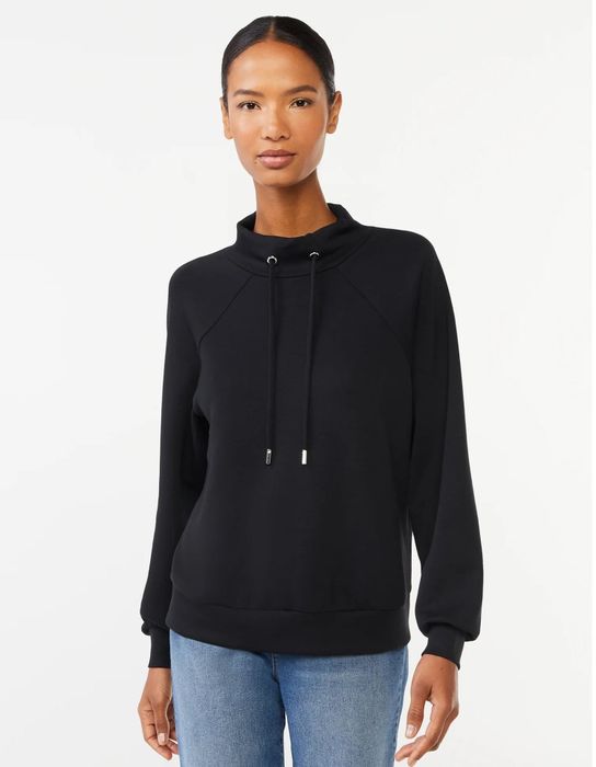 Person modeling a relaxed-fit sweatshirt with a high neckline and drawstring details, paired with jeans