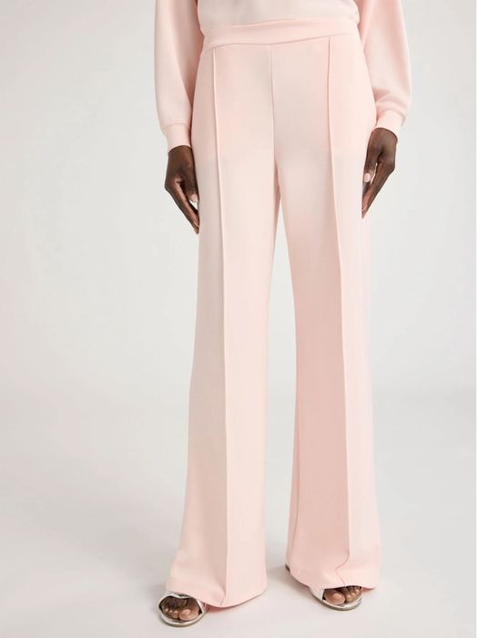 A person styling a chic outfit featuring wide-leg trousers, presented in a shopping context with a fashionable vibe.