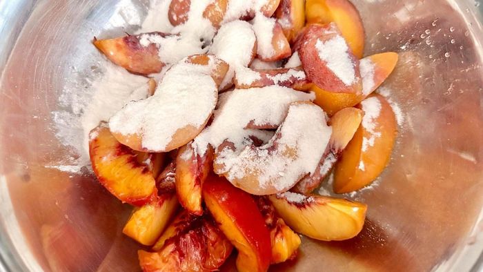 Sliced peaches in a bowl with a sprinkle of sugar and cornstarch on top.