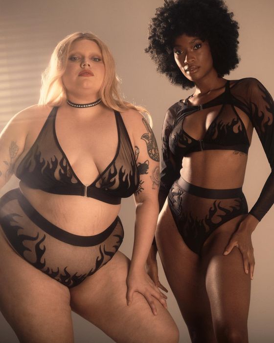 Two models strike a pose in matching black lingerie adorned with a striking flame pattern.