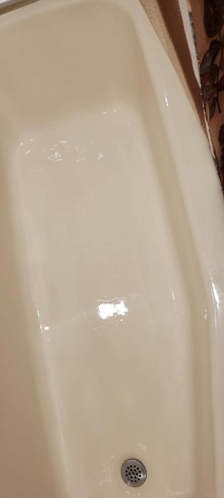A sparkling bathtub with a subtle light reflection on its surface, showcasing the drainage hole at the bottom