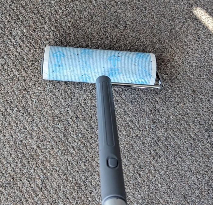 A hand scrubbing grout on a tiled floor, with visible dirt in between the tiles