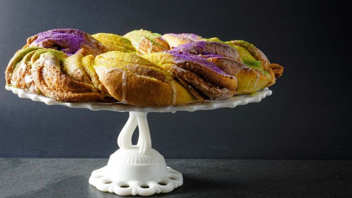 A vibrant king cake displayed on a cake stand.