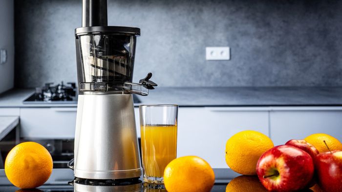 An electric juicer surrounded by various fruits ready for juicing