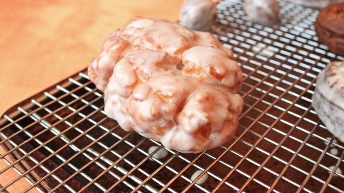A freshly baked apple fritter resting on a cooling rack.