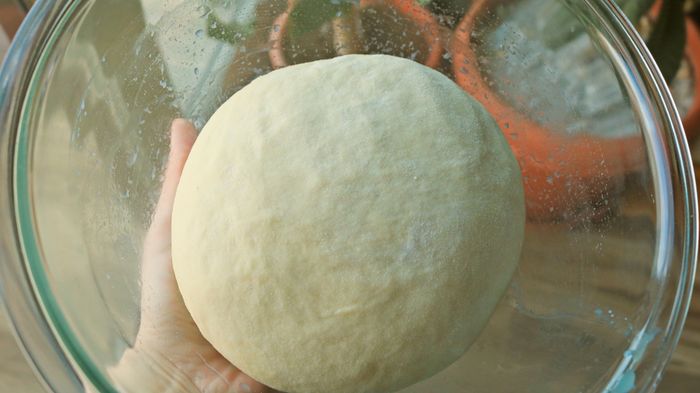A ball of dough sitting in a glass bowl.