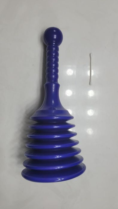 A blue rubber plunger with a ridged design sits next to a single cotton swab on a white surface.