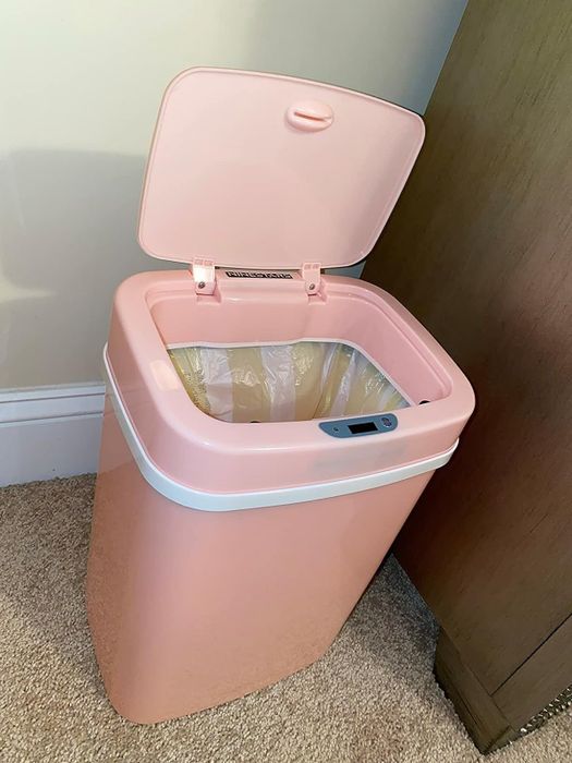 The pink trash can with the lid opened.