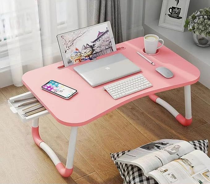 A pink laptop table with electronics and a coffee mug placed on it.
