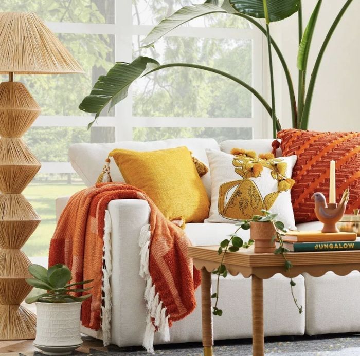 An orange, chunky woven throw blanket draped over a couch