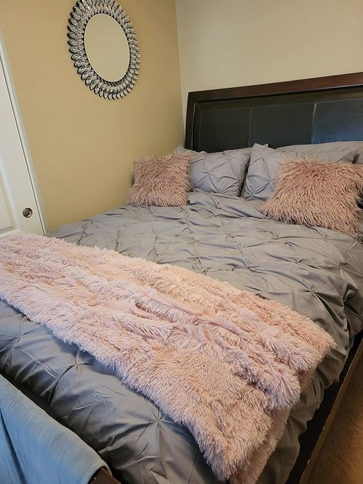 A pink blanket from the reviewer placed on grey bedding.