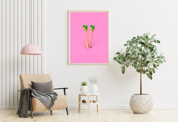 The pink digital print featuring a girl with green heels, framed and hanging on a wall.