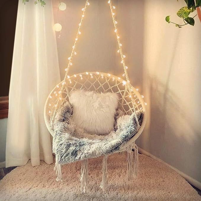 The illuminated hammock chair with a cozy blanket draped over it.