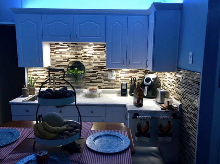 A kitchen illuminated by blue LED lights beneath the cabinets.