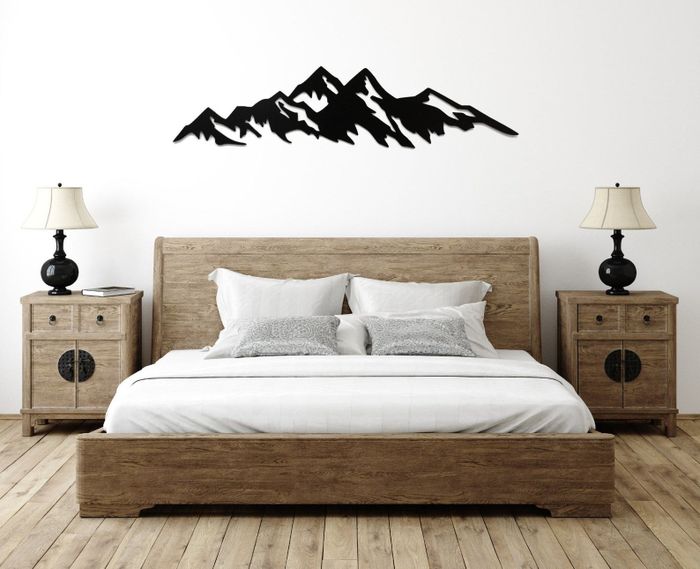 A sleek black metal mountain range placed above a bed