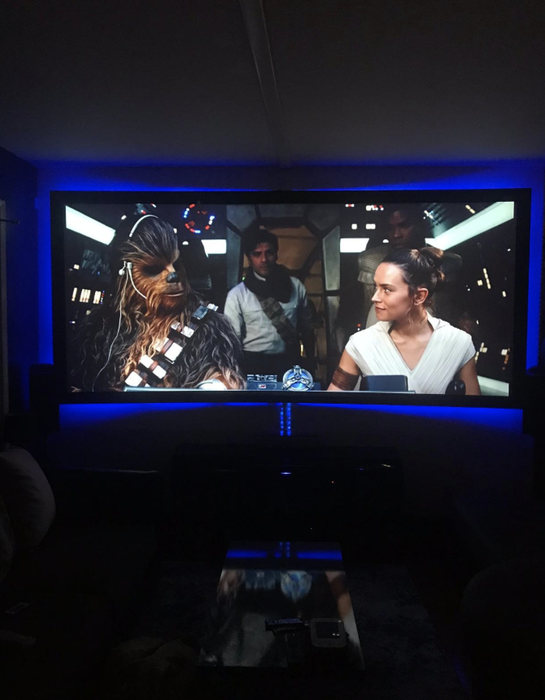 A television displaying Star Wars, surrounded by a blue backlight.