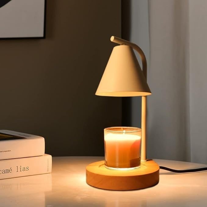A small table lamp lighting a candle on a wooden base, positioned next to two closed books on a minimalist table