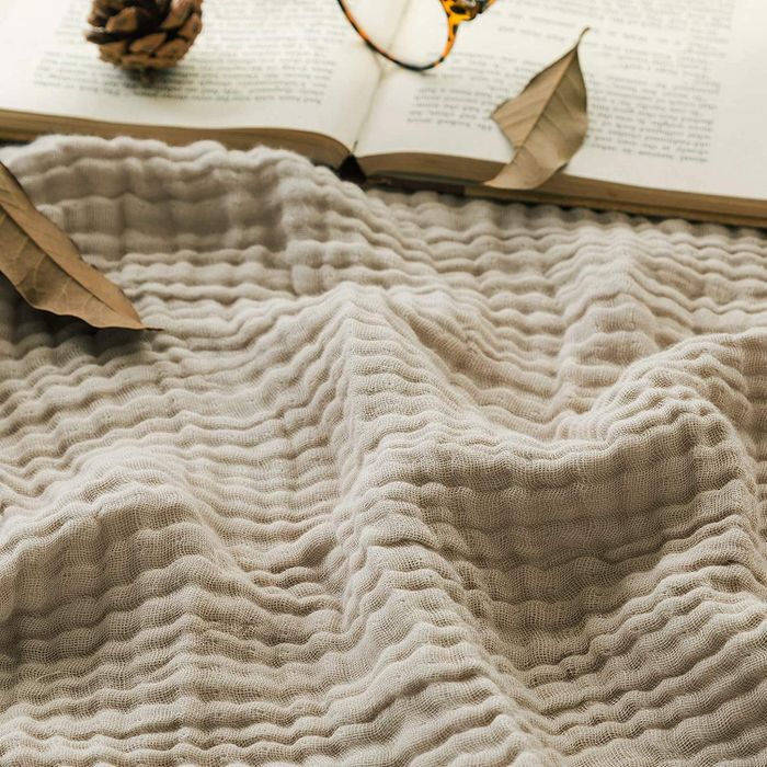 A close-up of the soft white muslin throw blanket, highlighting its textured fabric.