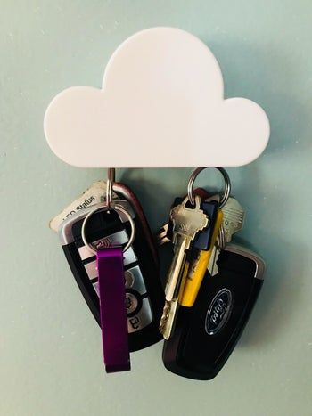 A sleek cloud magnet attached to a wall, holding two sets of car keys.