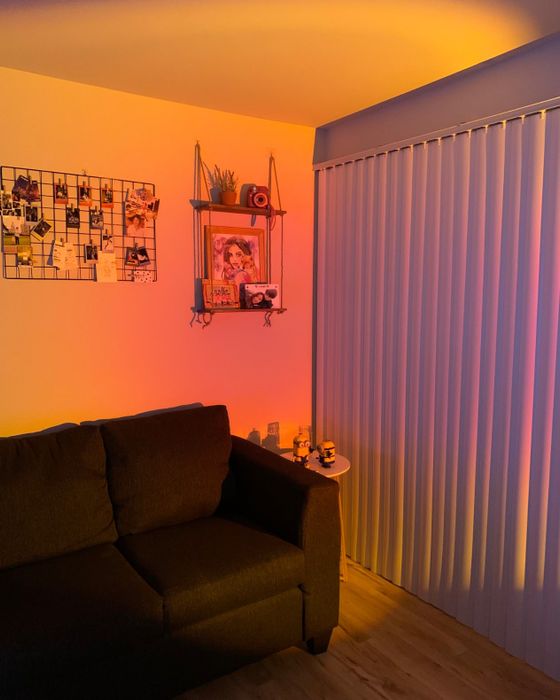A warm blend of orange and pink light casts a cozy glow on the walls of a living room.
