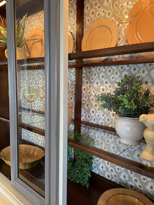 The reviewer's cabinet features a backdrop adorned with peel-and-stick daisy wallpaper.
