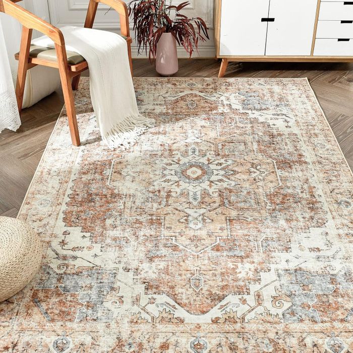 A patterned area rug laid on a wooden floor, with a chair and a cream-colored throw draped over it.
