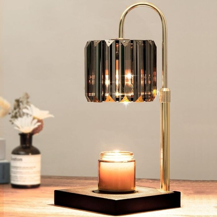 A chic table lamp with a geometric shade that casts light onto a lit candle below, perfect for setting a cozy mood