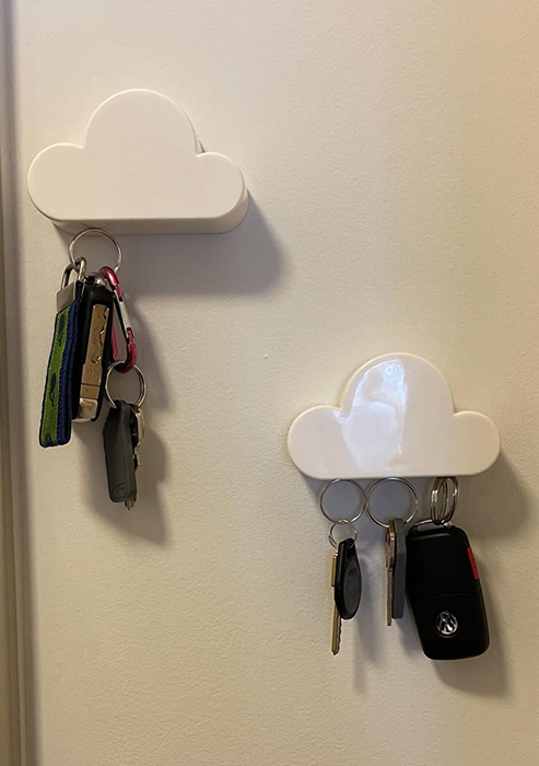 Two small cloud magnets, positioned at an angle, each holding a different set of keys.