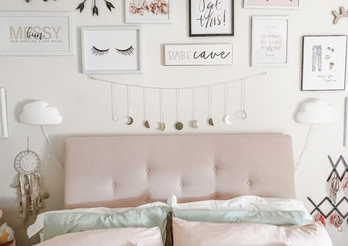 A bedroom wall featuring the moon phase garland, with art displayed alongside it.