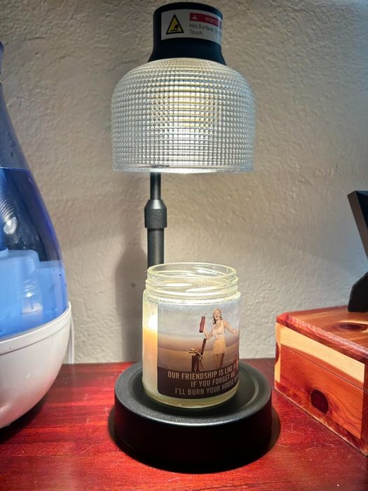 A lamp casts light on a candle with a humorous label reading,