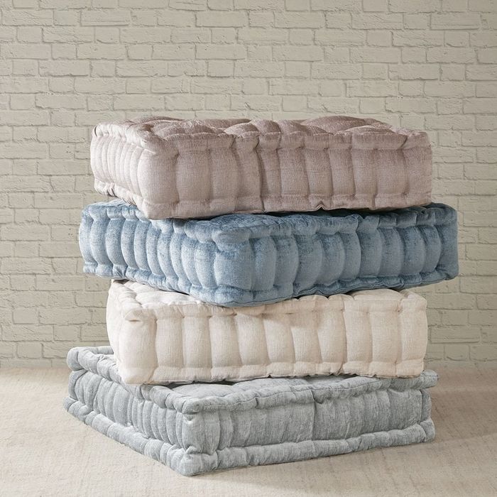 Four square tufted floor pillows neatly stacked on top of each other.