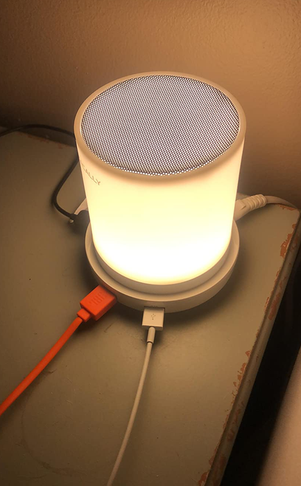 A close-up of the LED touch lamp, glowing gently, with multiple cords plugged into the USB ports.