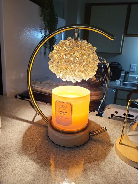 A reviewer's candle resting on a candle warmer