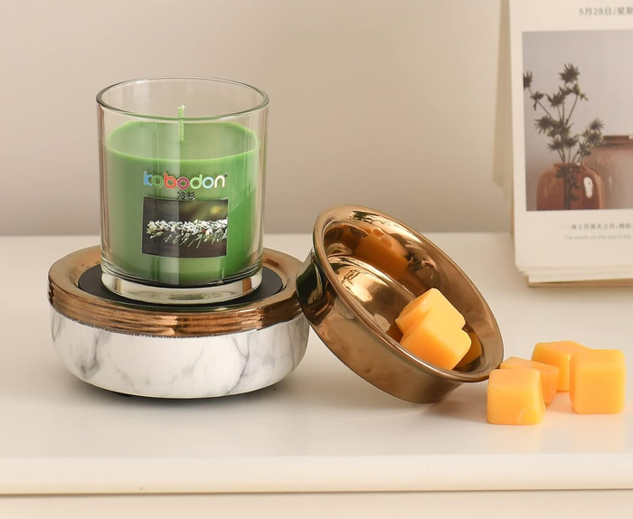 A candle resting on a candle warmer with a marble base