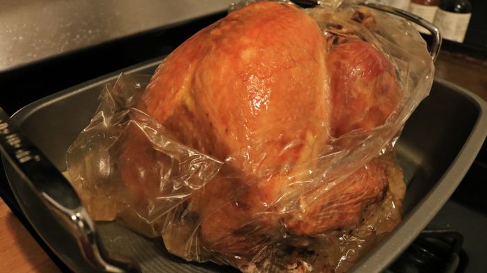 A fully roasted turkey with the roasting bag opened to reveal the top of the bird.
