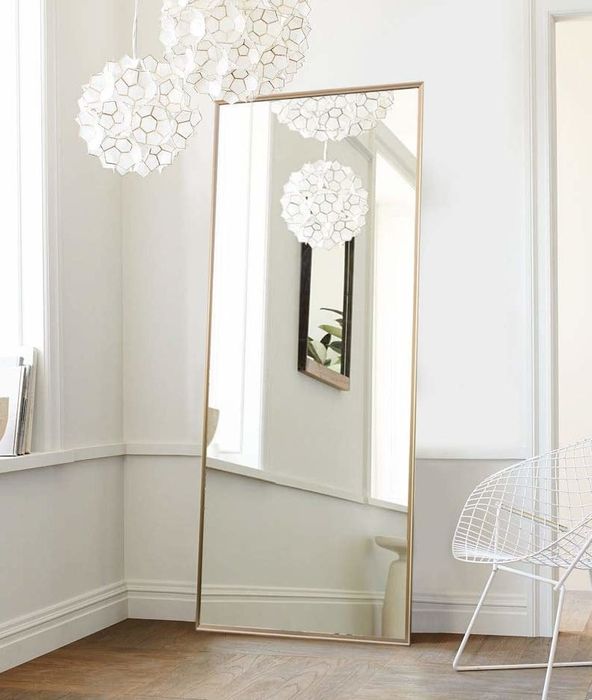 A rectangular full-length mirror framed in gold
