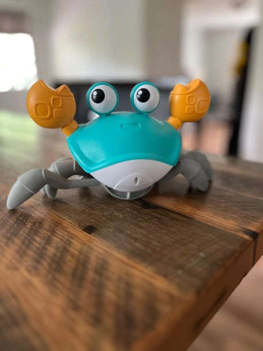 A toy crab with large eyes and orange claws on a wooden table