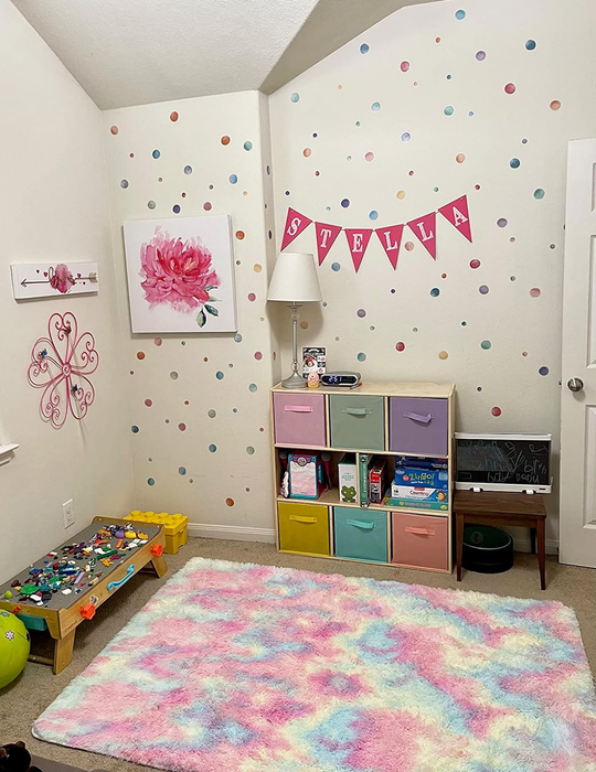 A white wall adorned with pastel-hued stickers resembling soft, round watercolor splashes.