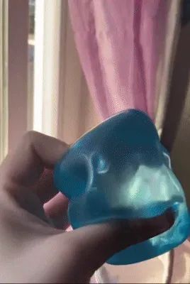 A hand squeezing a blue, translucent silicone toy