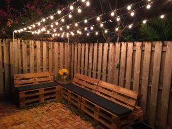 A reviewer's photo of string lights hanging in lines above a patio area with benches.
