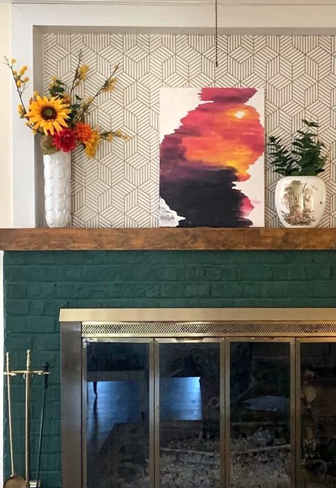A cozy fireplace with a chic gold and white geometric wallpaper above the mantel, adding a touch of modern sophistication to the room.