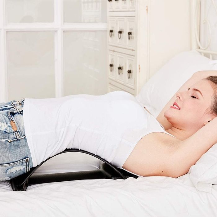 A person using the Magic Back Stretcher Lumbar Support Device for relief.