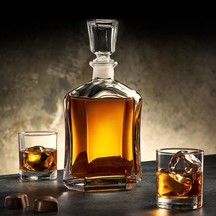 A glass decanter with a faceted design, filled with whiskey, topped with a matching glass stopper.