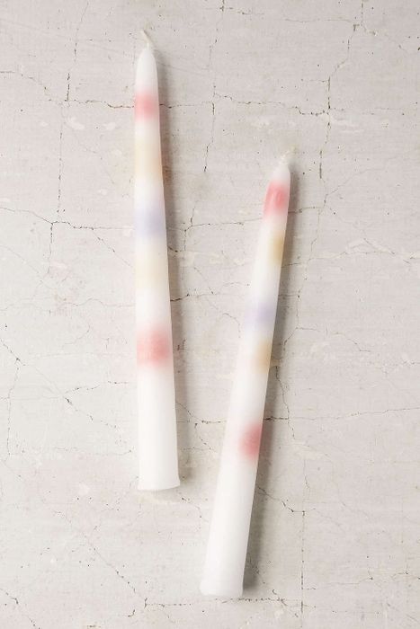 Two white candleholders with drops of colored wax inside