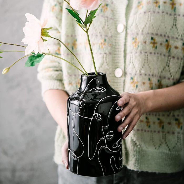 Model holding the black vase filled with a fresh bouquet of flowers