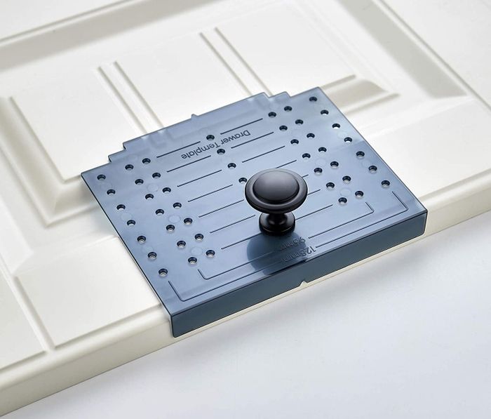 A close-up of the template placed against a cabinet door, designed with holes on both sides for easy pencil markings.